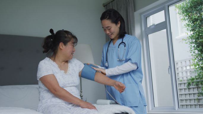 微笑的亚洲女医生在医院为快乐的女病人量血压