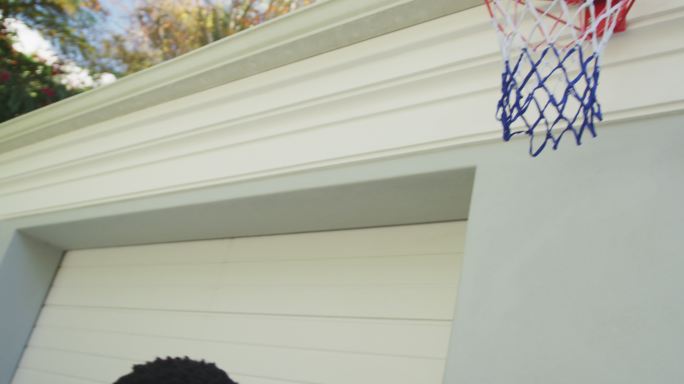 非裔美国爸爸抱着他的儿子在篮筐里灌篮