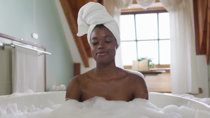 快乐的非洲裔美国人有吸引力的女人放松在浴室的泡沫浴