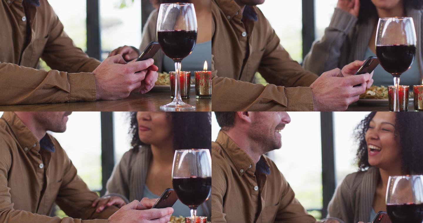 在饭店吃午餐的混血儿夫妇一边用智能手机一边微笑