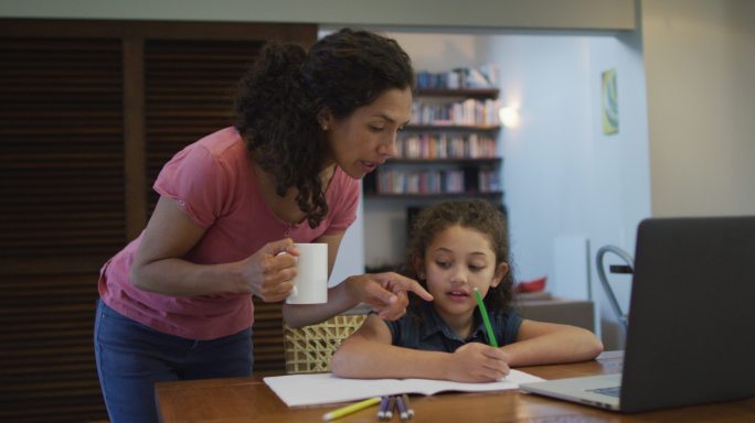 快乐的混血儿妈妈和女儿一起在家里做作业