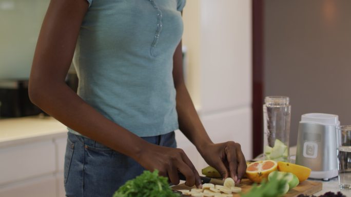 非裔美国人迷人的女人在厨房切蔬菜做冰沙