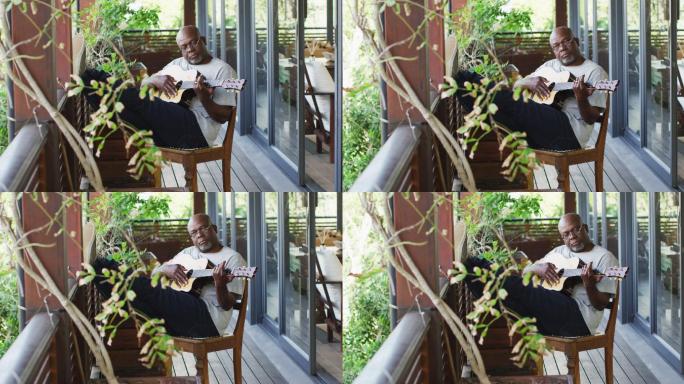 深思熟虑的非洲裔美国老人坐在阳台上弹吉他