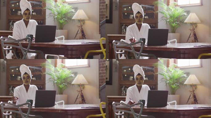 非裔美国美女，带着面膜喝咖啡，在家里用笔记本电脑