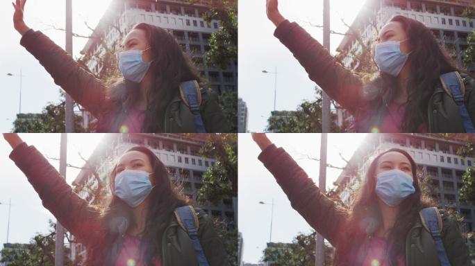 戴着口罩站在街上叫出租车的亚洲女性