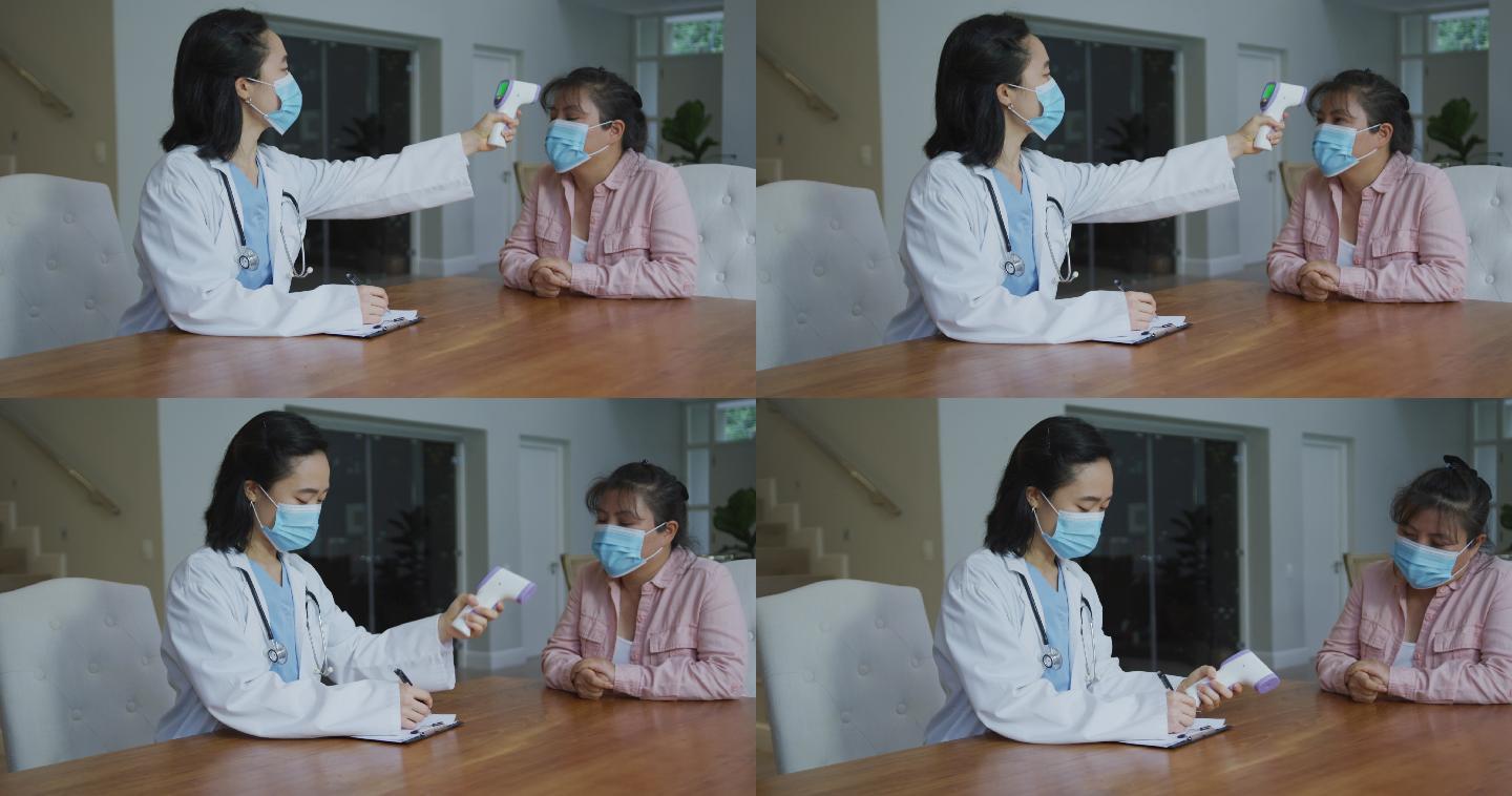 戴口罩的亚洲女护士在医院为戴口罩的女病人量体温