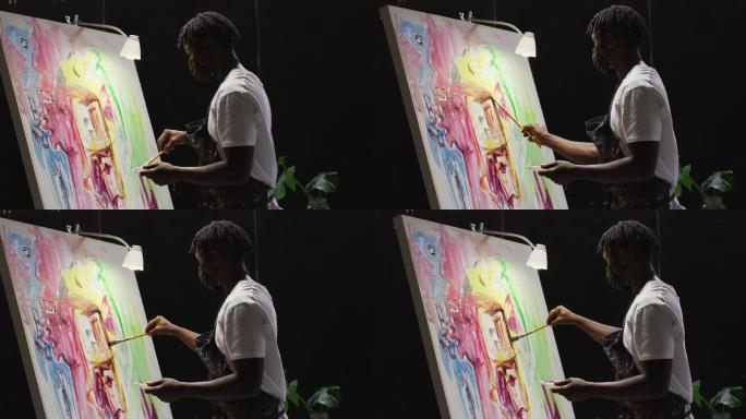 非裔美国男性艺术家穿着围裙在画布上画在艺术工作室