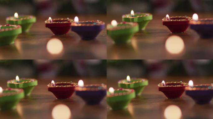 四根点燃的蜡烛在装饰陶罐在木制桌面，散景火焰在前景