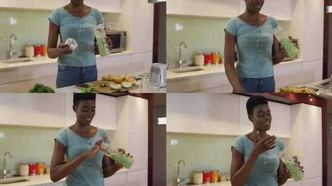 微笑的非洲裔美国人迷人的女人品尝自制冰沙在厨房