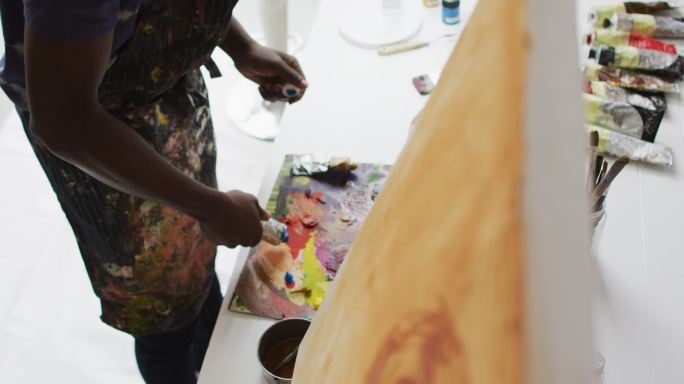 中部的非裔美国男性画家在艺术家工作室混合颜料