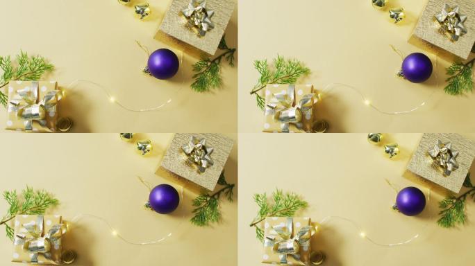 黄色背景上的金色和紫色圣诞装饰和礼物的视频