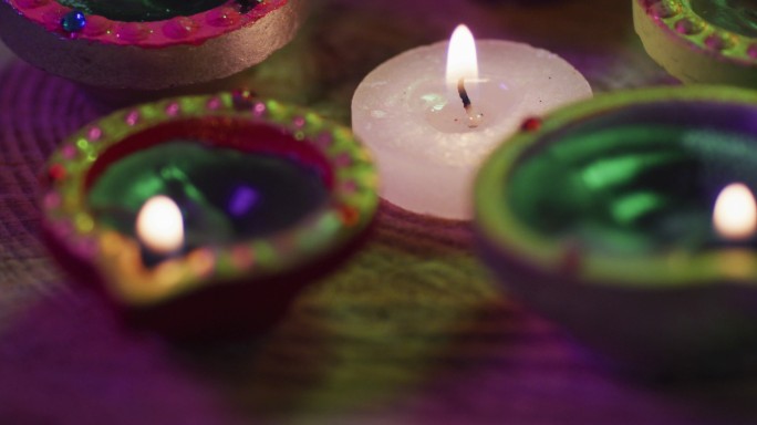 点燃的蜡烛在装饰陶罐和茶蜡烛在木制的桌面，散景背景