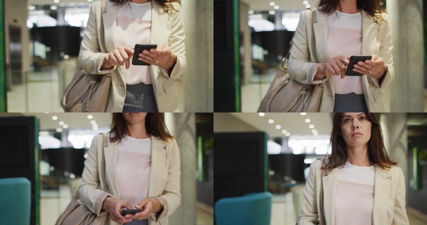 白人女商人在现代办公室走廊使用智能手机