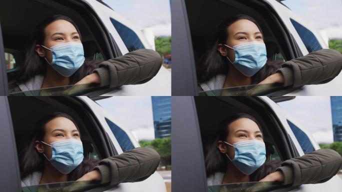 一位戴着口罩坐在车里望向窗外的亚洲妇女