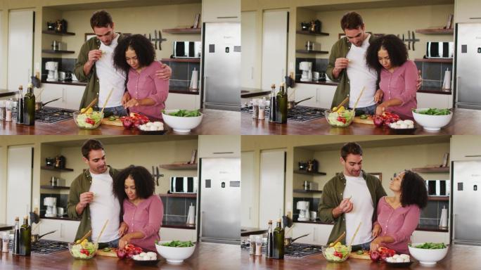 幸福的不同的夫妇一起在厨房准备食物，切蔬菜沙拉
