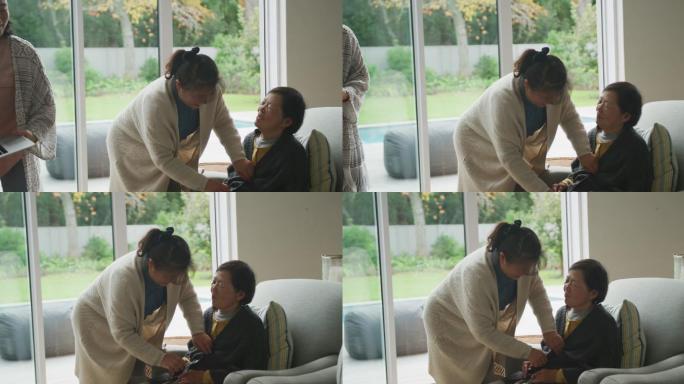 快乐的资深亚洲母亲舒适的扶手椅由成年女儿在客厅