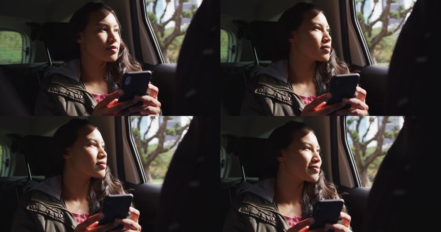 亚洲女性在车里使用手机微笑望向窗外