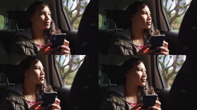 亚洲女性在车里使用手机微笑望向窗外