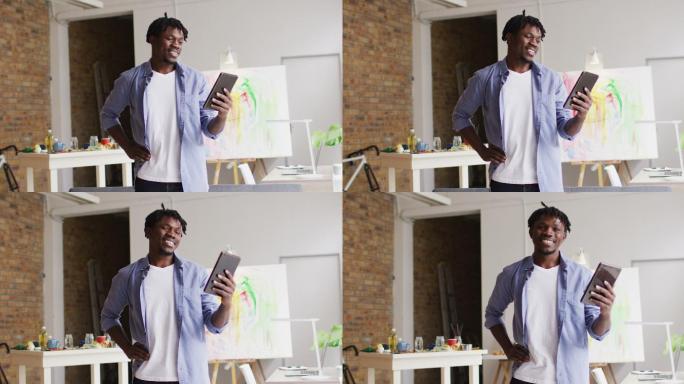 非裔美国男艺术家微笑，而在艺术工作室的数字平板电脑上有一个视频电话