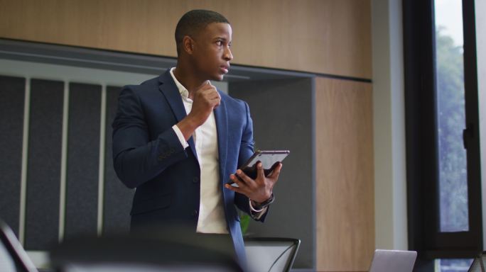 非裔美国商人在现代办公室的会议室使用平板电脑