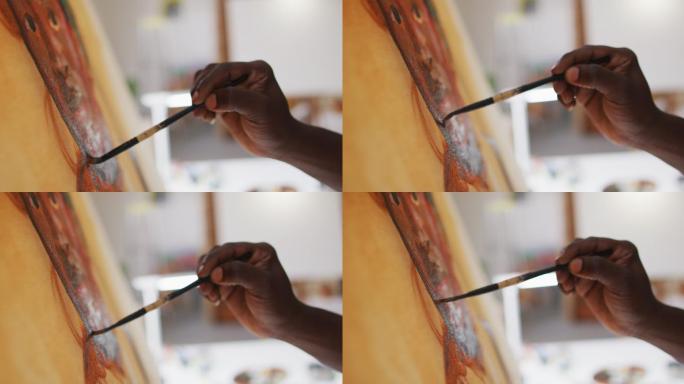 非裔美国男性艺术家穿着围裙在画布上画在艺术工作室