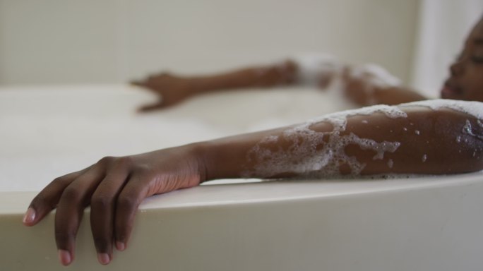 非裔美国人有吸引力的女人放松在浴室的泡沫浴