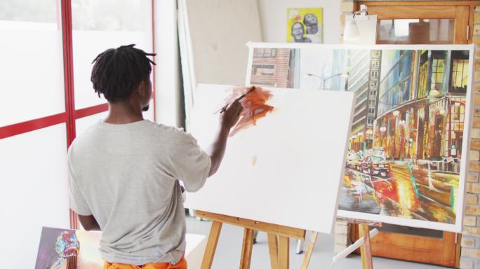 非裔美国男性画家在艺术家工作室的帆布上作画