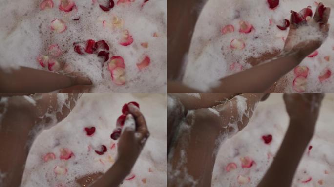 非裔美国美女的手用泡沫和玫瑰花瓣沐浴