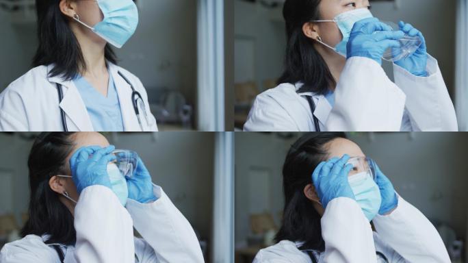 亚洲女护士在医院戴上防护眼镜，戴上口罩