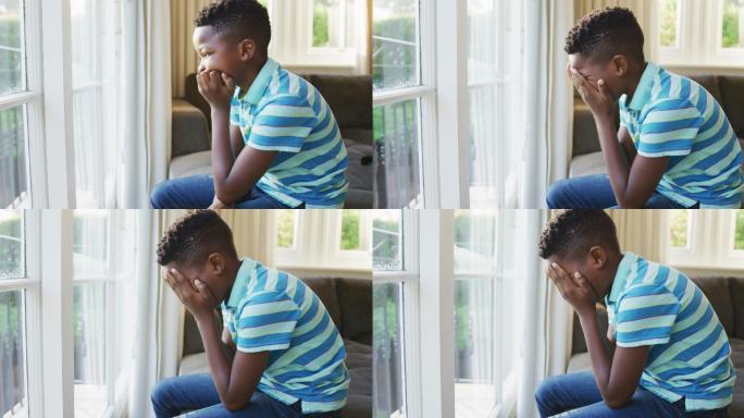 压力大的非裔美国男孩坐在家里的沙发上看着窗外