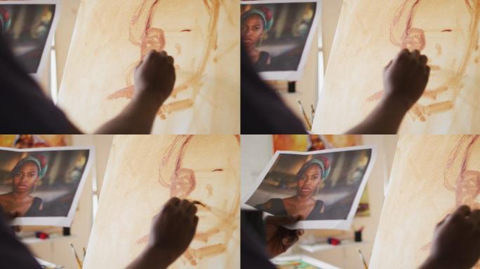 非裔美国男性画家从照片在画布上绘画在艺术家工作室