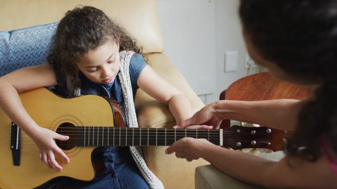 快乐的混血母亲和女儿一起弹吉他