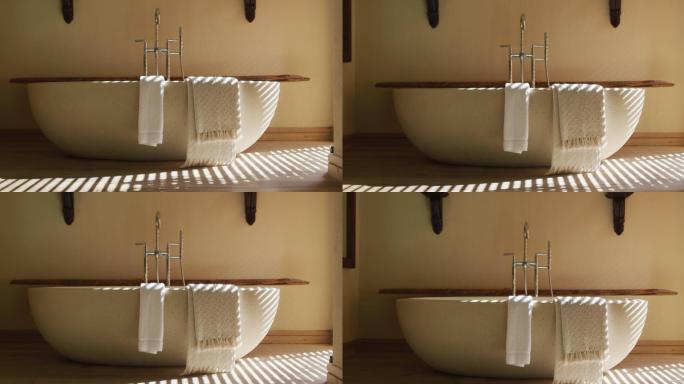 椭圆形白色浴缸在最小的现代浴室，阳光透过百叶窗