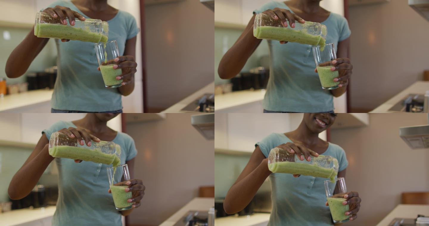 非裔美国美女的手在厨房里把自制的冰沙倒进玻璃杯里