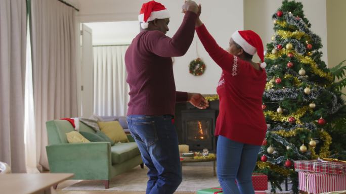 快乐的非裔美国老夫妇在客厅装饰圣诞树