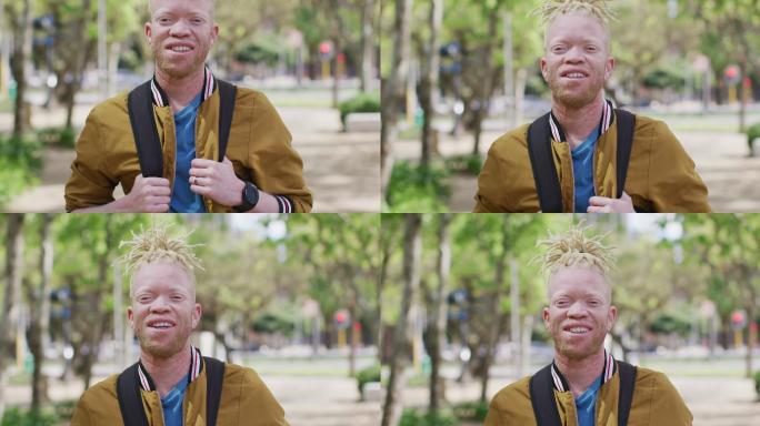 微笑的白化病非裔美国人肖像与雷鬼头发在公园看着相机