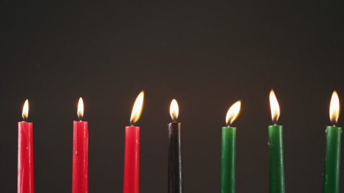 在黑色的背景下，万圣节的绿色、黑色和红色蜡烛的组成