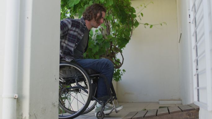 一个坐轮椅的白人残疾人进入他的家门