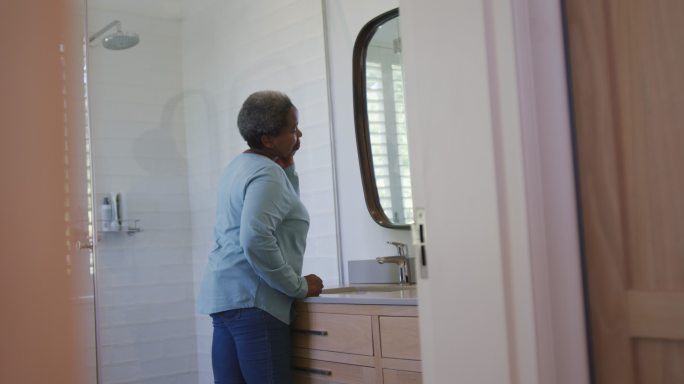非裔美国高级女性在浴室里看镜子