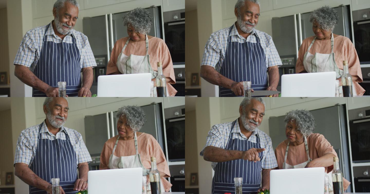 快乐的非裔美国老年夫妇用笔记本电脑一起做饭