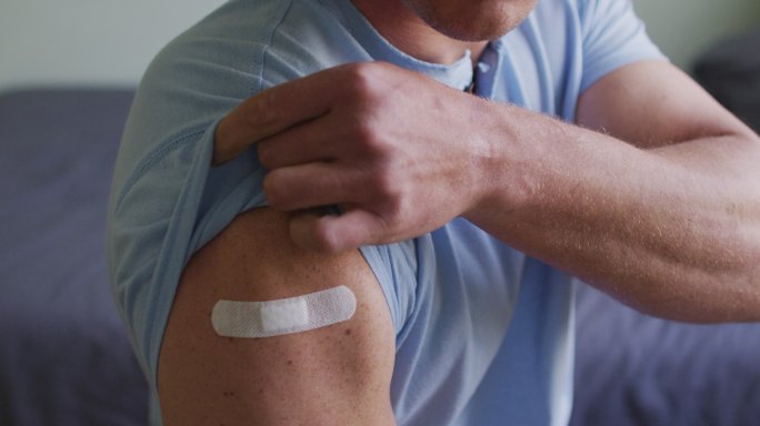 白种人男子接种新冠肺炎疫苗后手臂缠绷带的上半身