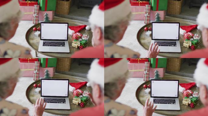 白种人老夫妇戴着圣诞老人帽，在圣诞节期间用笔记本电脑进行视频通话，还有复印空间