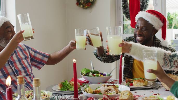 快乐的非裔美国人多代家庭戴着圣诞帽，庆祝节日大餐