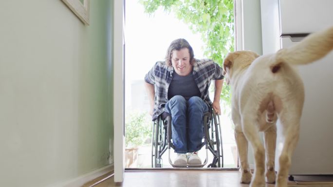 快乐的坐轮椅的白人残疾人带着他的狗进屋