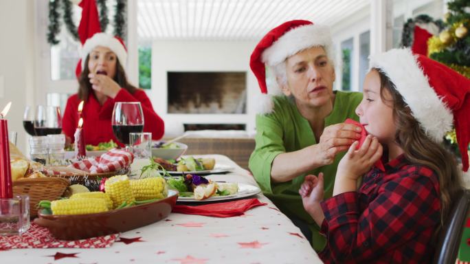 快乐的白人奶奶在圣诞餐桌上给孙女擦嘴