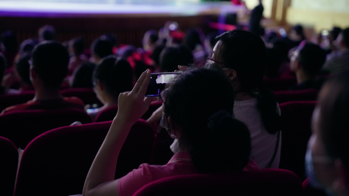 观众席上观看孩子表演的家长手机拍照视频