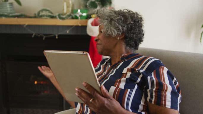 快乐的非裔美国老年妇女打手势，圣诞节期间视频通话