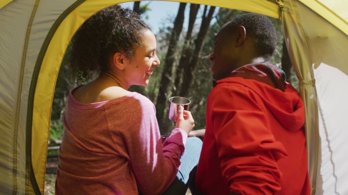 微笑的夫妇坐在帐篷和喝茶在农村