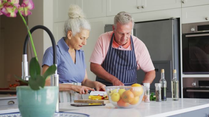 白种老年夫妇穿着围裙在厨房一起做饭