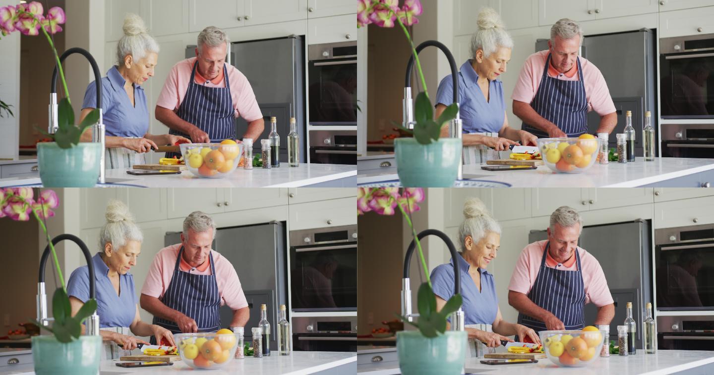 白种老年夫妇穿着围裙在厨房一起做饭